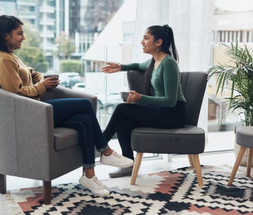 Shot of two young women drinking coffee while sitting together at home.