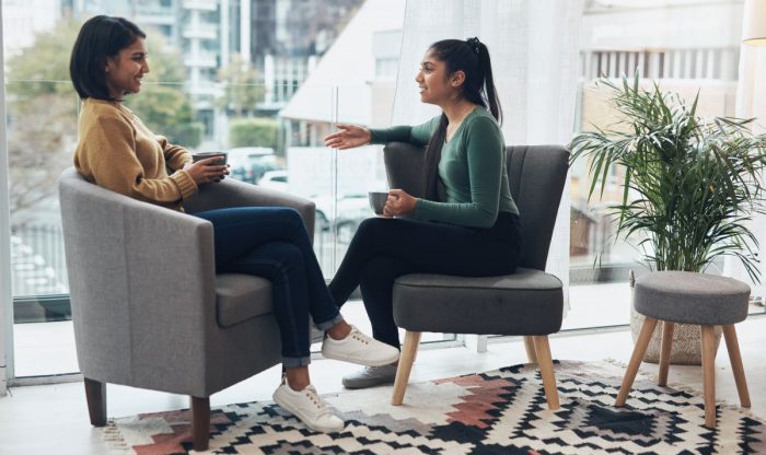 Shot of two young women drinking coffee while sitting together at home.